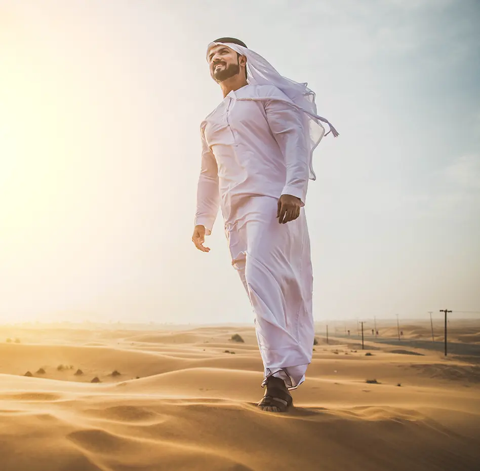 Man wearing a formal Al-Dar Apparel Emarati style thobe walking in the desert